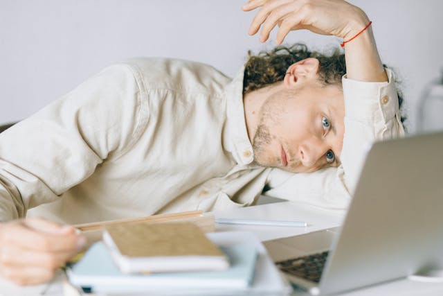 man suffering burnout slumped on desk in front of computer